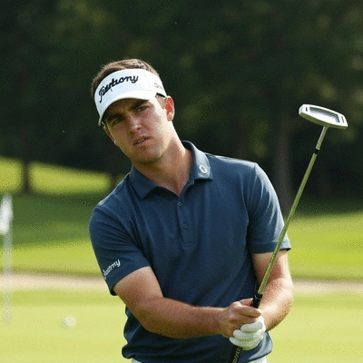Golfer holding a putter, looking focused, with a blurred golf course in the background, symbolizing mental fortitude and concentration