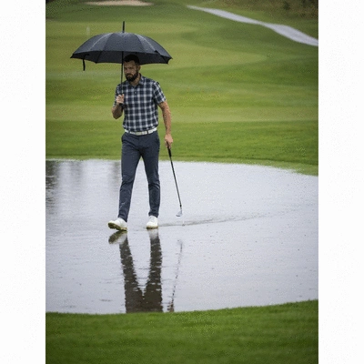 Golfer with umbrella on a wet golf course